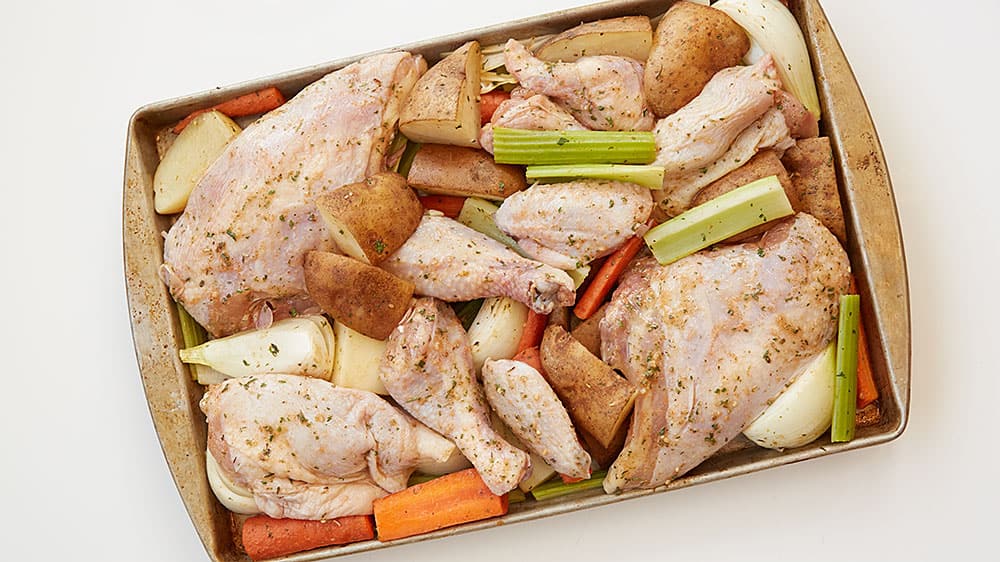 Chicken, celery, carrots and potatoes on a baking sheet