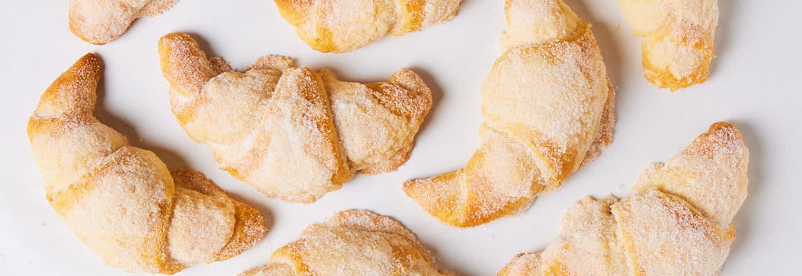 Freshly baked crescent rolls heavily coated in a fine cinnamon-sugar dusting.
