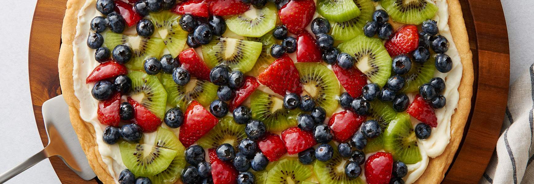 Fruit pizza with kiwi and berries on a round crust.