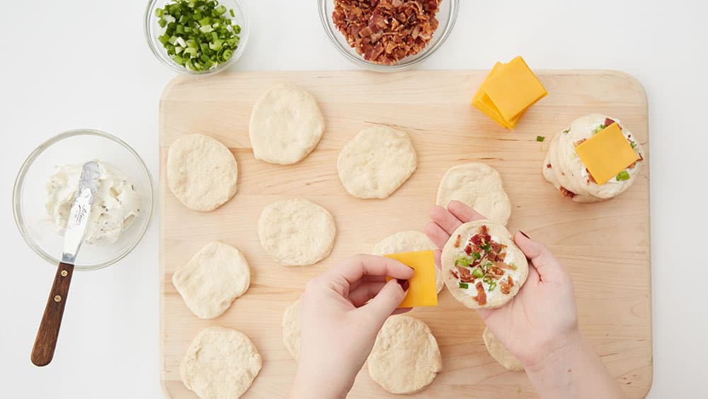 Top each layer with cream cheese, bacon, green onions, and cheddar