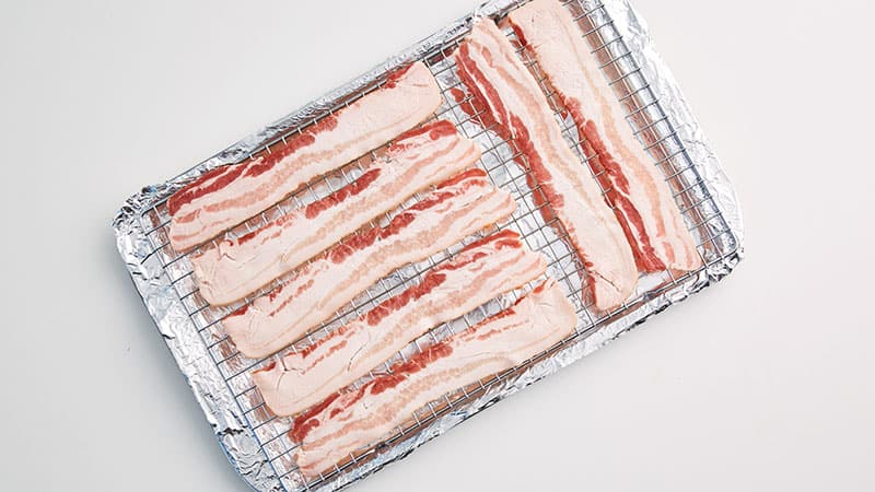 Place an oven-safe baking rack on top of the baking sheet and then place the bacon strips on top of that.
