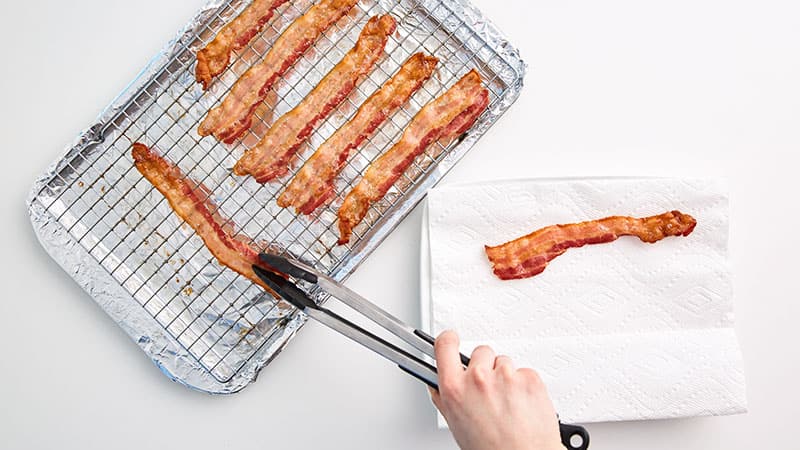 Using tongs, remove bacon from baking sheet and place each strip on a paper towel-lined plate.