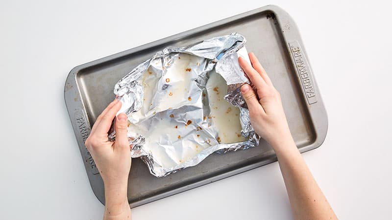 Allow the grease to cool and solidify on the foil and then crumple it up, throw it out
