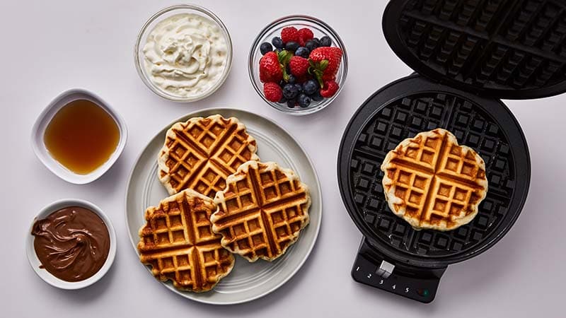 Waffle iron, waffles, nutella, syrup, berries, whipped cream.