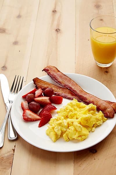 Scrambled eggs, bacon, fruit, juice