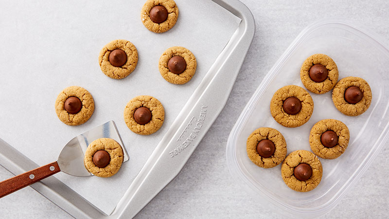 Peanut Butter Blossoms on a baking sheet and in a plastic container