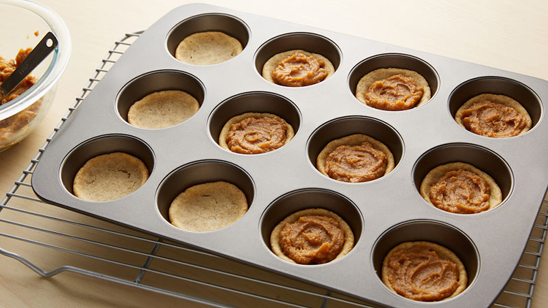 Press cookie dough in bottom of each muffin cup. Top each pie cup with pie filling.
