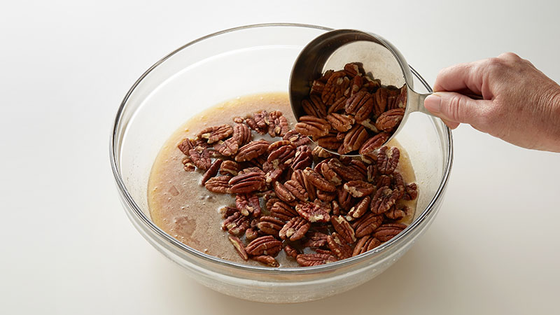 Pecans, melted butter, brown sugar in a glass bowl