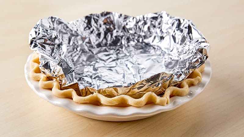 Pie dough and aluminum foil in a pie plate