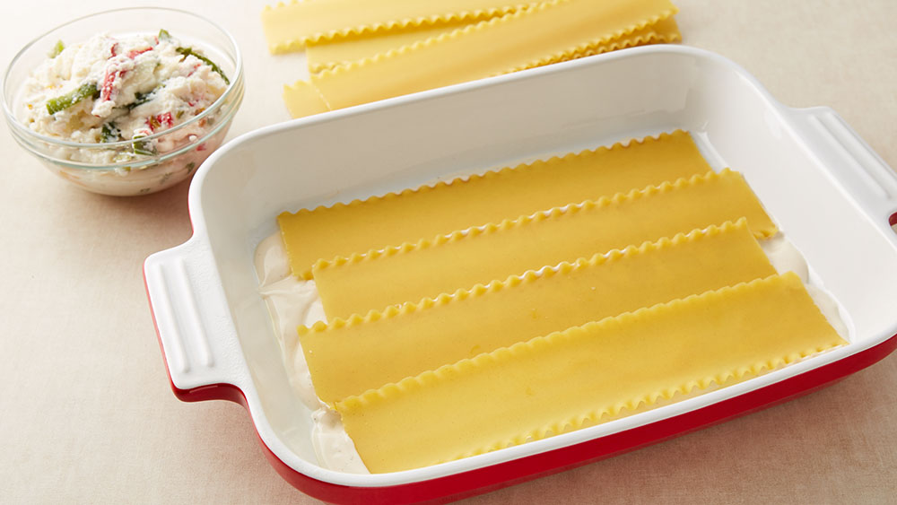 Arrange 4 uncooked lasagna noodles over sauce.