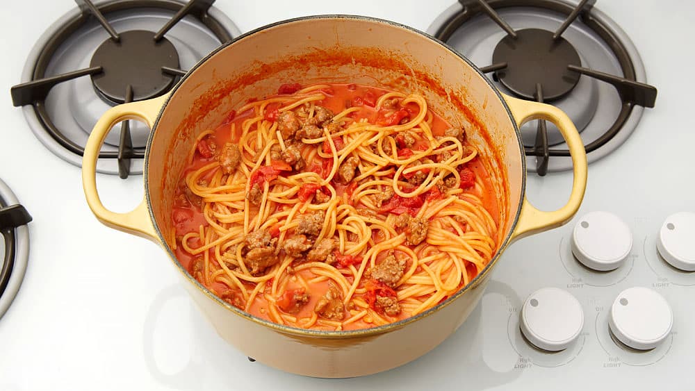 Pasta, spaghetti and sausage in a pot on the stove.