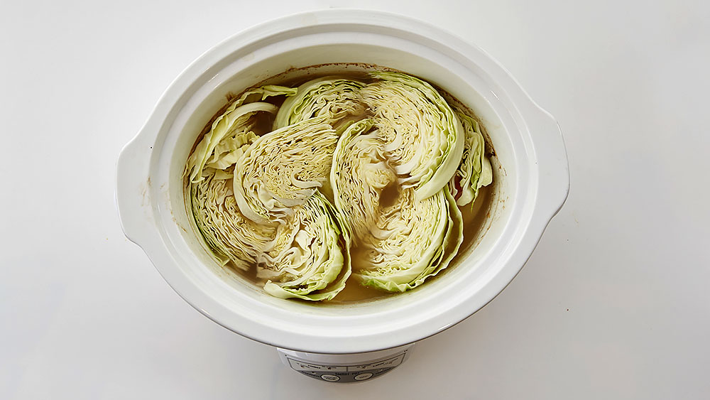 Add cabbage wedges to vegetables and broth in slow cooker. 
