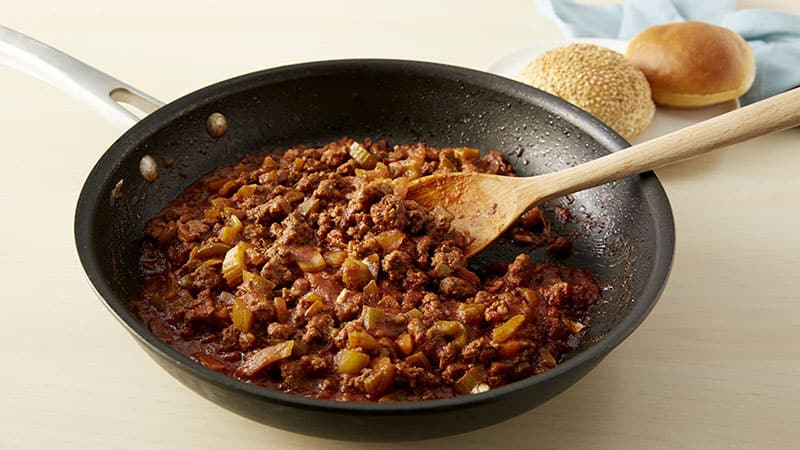Combine browned ground beef, green bell pepper, onion, brown sugar, mustard, vinegar, tomato sauce in a skillet.
