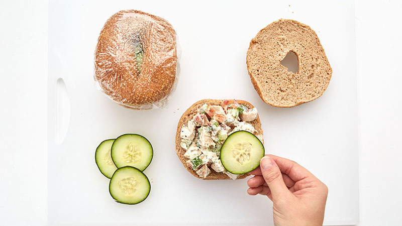 Spread chicken mixture on bottom halves of bagels. Top with cucumber slices.