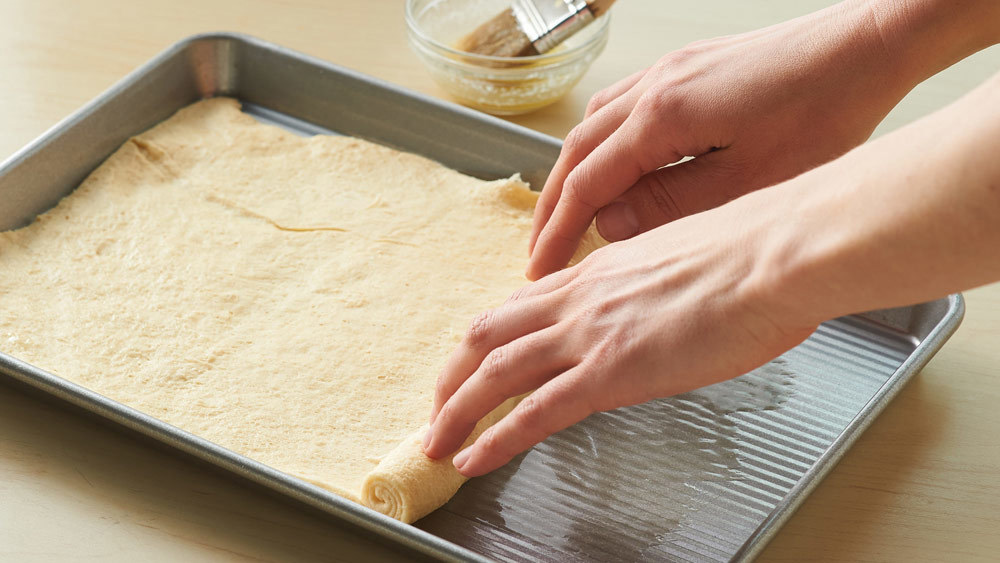 Unroll and press one can of dough over the melted butter mixture.