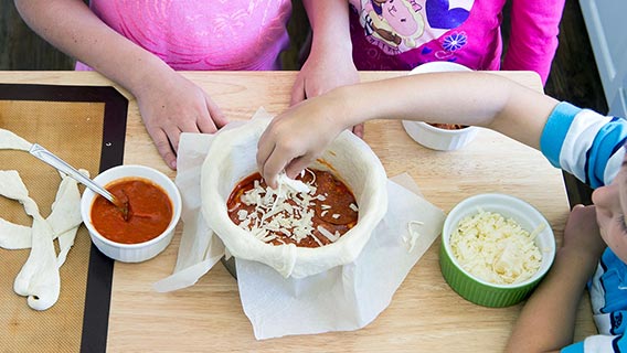 Adding shredded mozzerella and tomato sauce to pizza pan