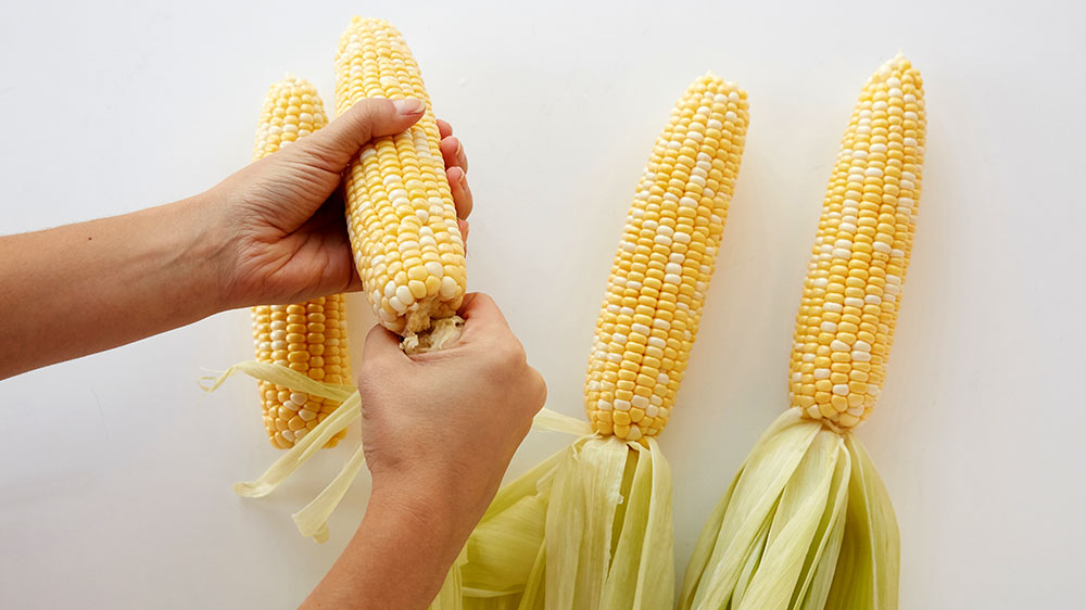 Remove the husk leaves from the corn on the cob.