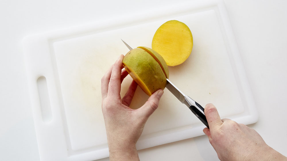 Stand the mango, stem end down, and hold. Starting at top, place knife about 1/4 inch from widest center line, and cut down through mango. 