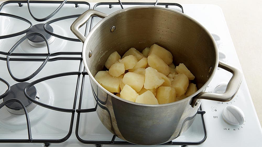 Peeled, cubed potatoes in a pan on the stove