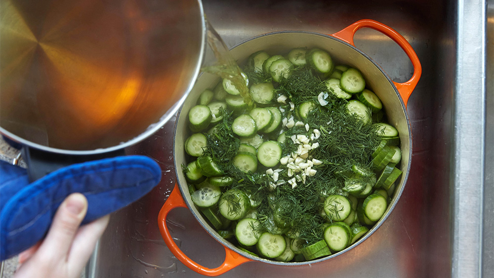 Pour water and apple cider into pot with sliced cucumbers