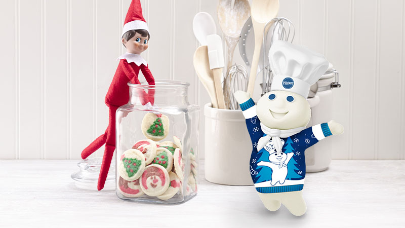 Elf on the Shelf in the cookie jar, with the Pillsbury Doughboy