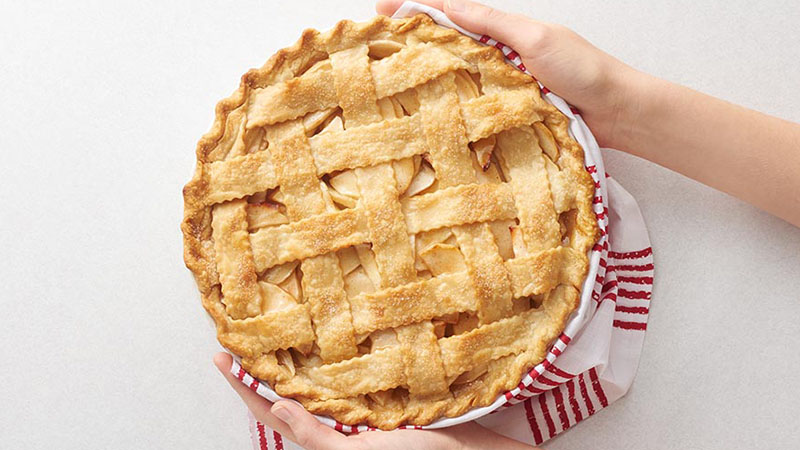 Hands holding a lattice-crust apple pie