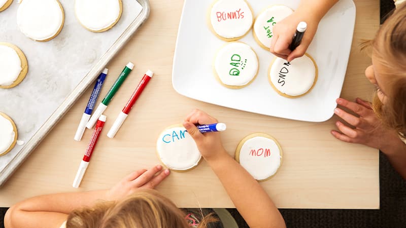 Kids writing on frosted sugar cookies