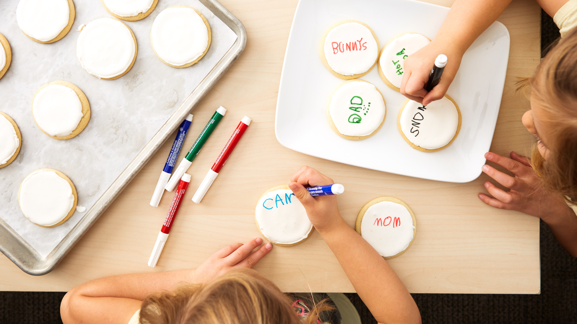 Kids writing on frosted sugar cookies