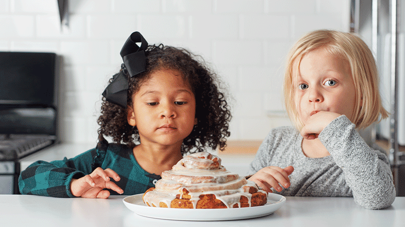 Two young girls eating a giant cinnamon roll