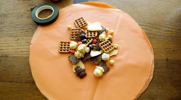 orange tablecloth cut into circle, serving of party mix in the center