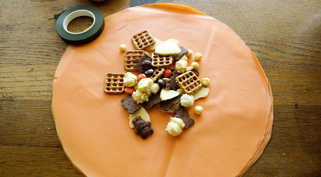 orange tablecloth cut into circle, serving of party mix in the center