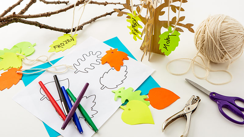 Tree branches, construction paper leaves, scissors, twine, hole punch, pens