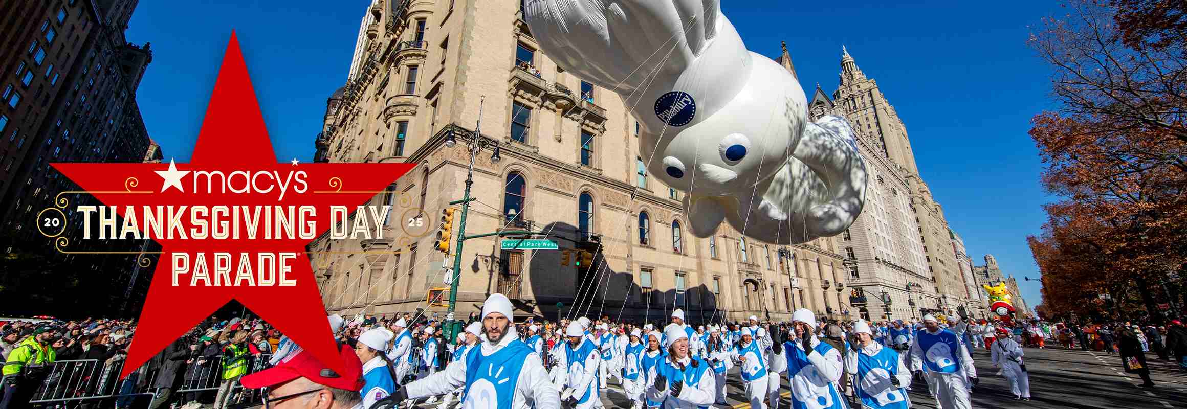 Doughboy balloon floating above the Macy’s Thanksgiving Day Parade. A red star is in front of the image with the words “Macy’s THANKSGIVING DAY PARADE” across it.