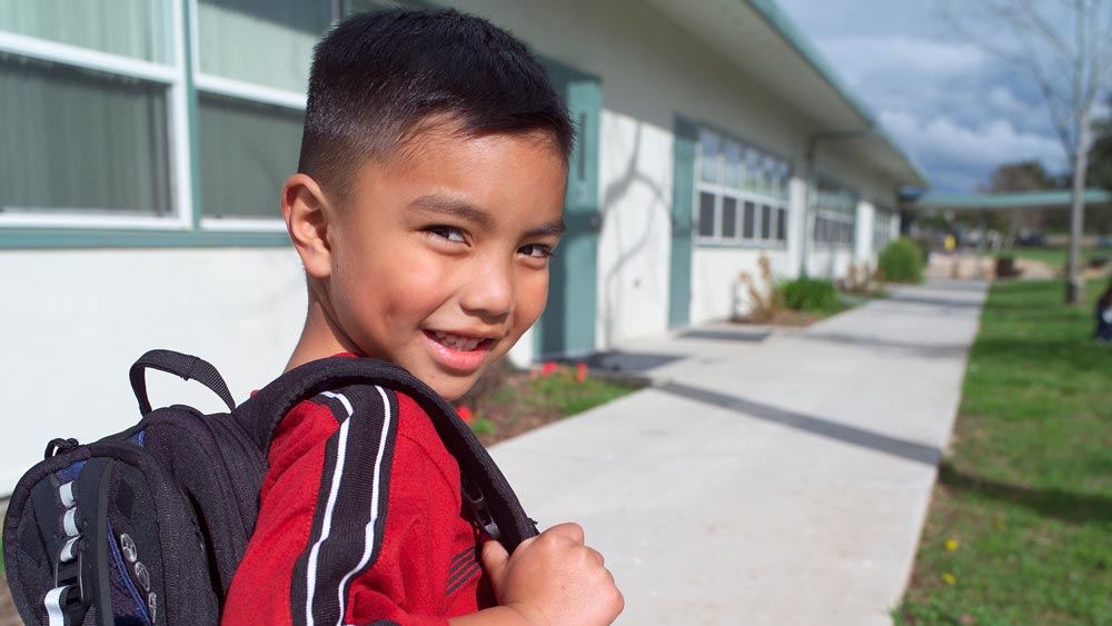 little boy with backpack walking outdoors